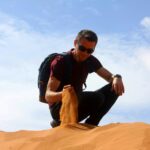 Man exploring the golden sand dunes of the Merzouga Sahara Desert in Morocco
