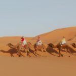 Happy travelers enjoying a camel ride during the 3 Days Marrakech to Fes Desert Tour